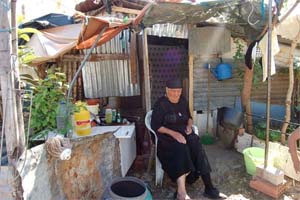 Idosa, à porta da sua habitação